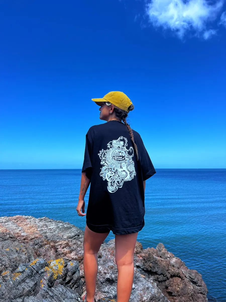 Oversized black t-shirt with white line art on the back, worn on the coast